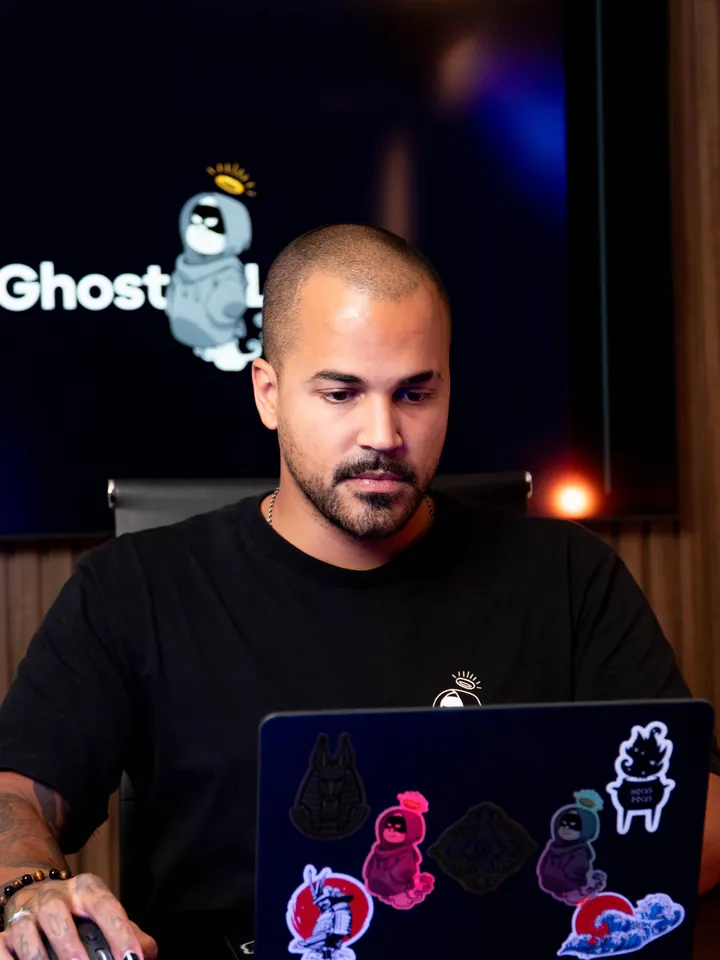 Thiago Dam concentrado en su laptop, en el estudio de Ghost Lab7, con el logo de la marca al fondo
